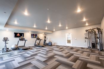 A gym with weights and cardio equipment and a wooden floor